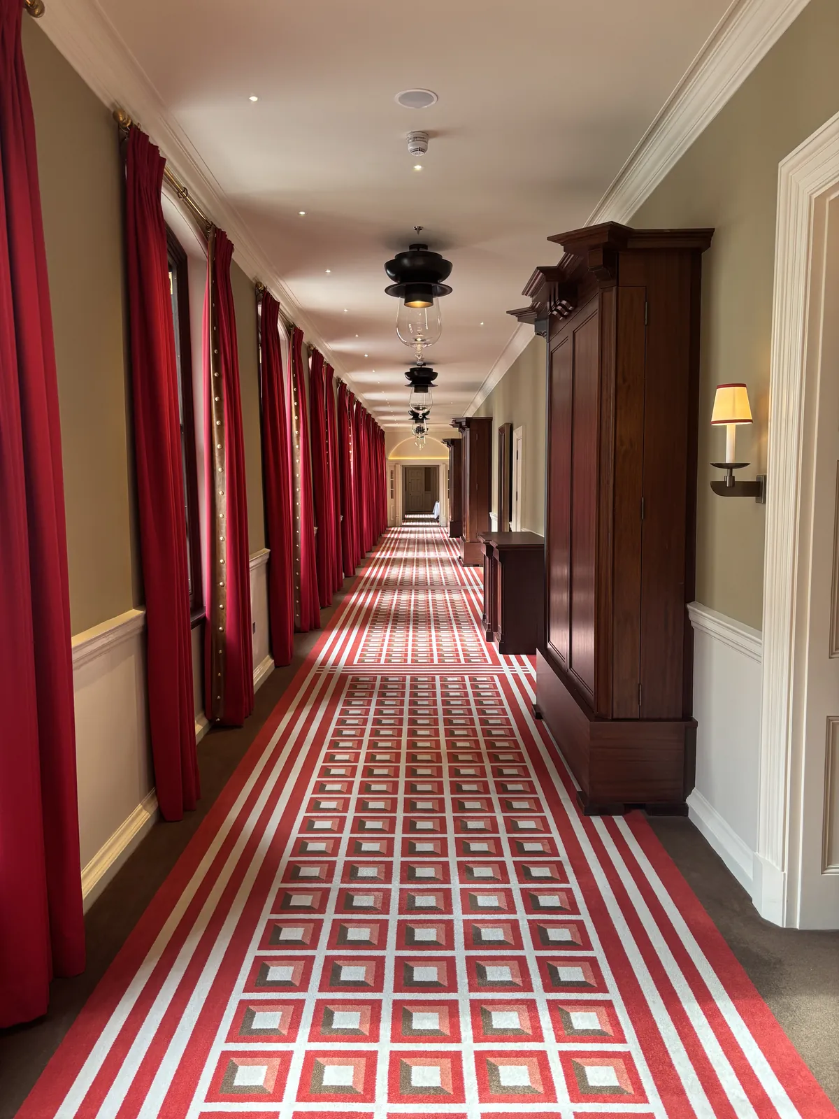 Long corridor with scarlet curtains and patterned carpet at Raffles London at The OWO